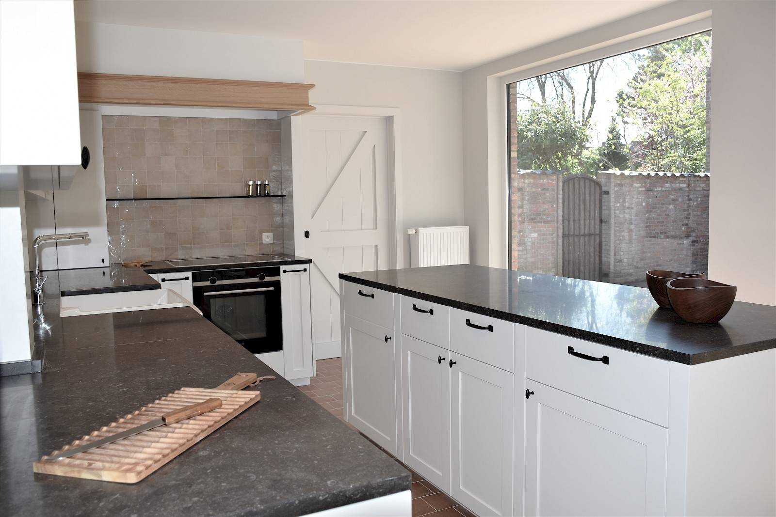Witte keuken met zwart keukenblad in een realisatie van Zinder. 